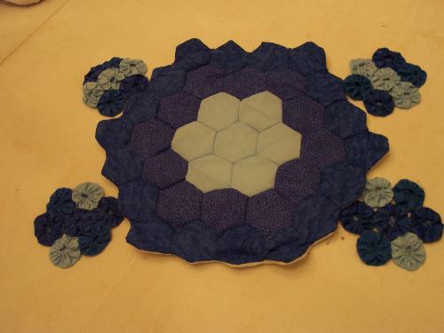 Blue centerpiece mat and set of 4 coasters - The centerpiece is made in the grandmother's flower garden pattern. The coasters are quilting yo-yos. All in shades of blue and handsewn.