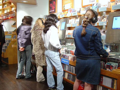 Check out before buying - Three ladies in a music store, checking out some new tunes before buying one.