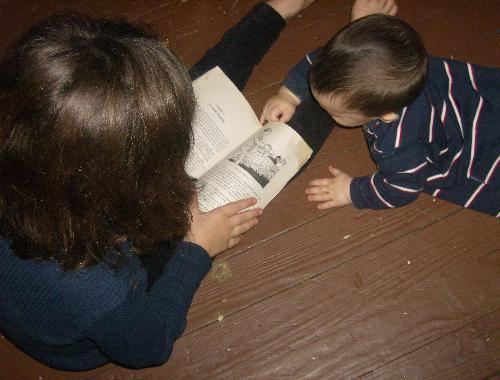 My daughter reading  - Here's my daughter reading a chapter book, and her baby brother coming to check it out.