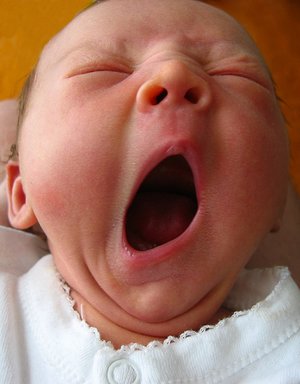 baby yawning, needing more sleep! - baby in a white shirt yawning in front of the camera