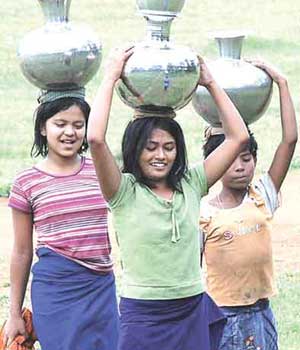 girls - Girls carrying water in pot in a village are of India.