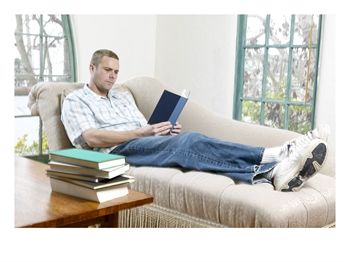 Relaxing With A Book - A man relaxing with a book, on the sofa.