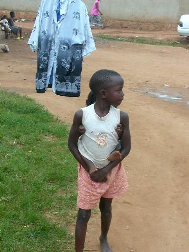 girl lifting her sister as she sells shirt behind. - Girl sported selling shirt while at the same time attending to her young sister at back.