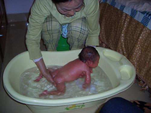 baby having a bath - this is my baby son having a bath by his aunt, who takes good care of him. He seems to be enjoyable of the water in the plastic tub.
