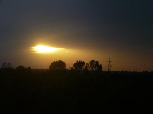 peeking out - As it sets, the sun peaks out of the sky, showering the horizon with its last golden glow.