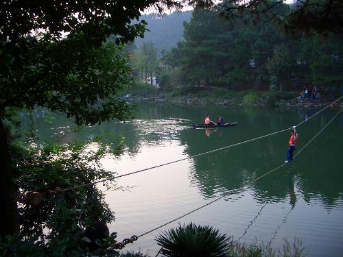 Here is one photo I took - Here is one of the photos that I took years ago for you to enjoy. The background you see in the photo is a scenic spot in our local place. You see a man walking on a rope from one side of the rope to the other over a big pond. He was just walking in the middle when I took the shot and I love this photo very much.