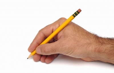 Writing Hand - Writing hand holds a pencil and writes on white a paper. It looks like office job, the writing is for business ideas.