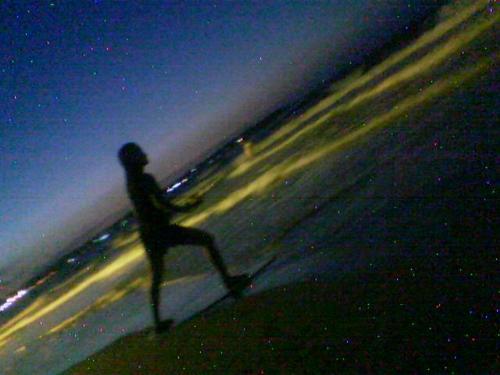 Night Surfing girl - Girl surfer poses at the seashore while darkness covers the earth.