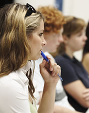 Girl chewing on a pen - A girl who wear a white shirt is chewing her pen while studying.