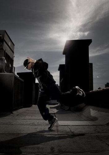 Chris Brown - Chris Brown being shot in an Air Jordan ad on a rooftop in New York. Gray and black background. Black outfit. Black Air Jordans.