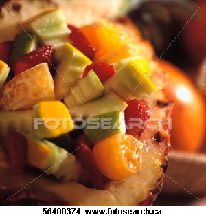 Fruit salad - Half a hollowed-out pineapple filled with fruit salad sitting next to a wooden bowl filled with fruit