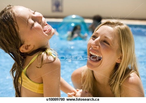 Having fun and laughing in the pool - Mom and daughter having fun, laughing and playing in the pool.