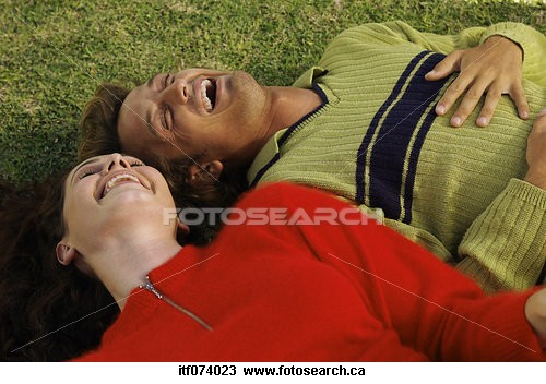 Picture of a couple lying on the grass looking up  - Couple lying on the ground laughing
