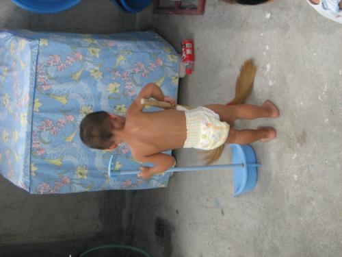little sweeper - a neighbor's child sweeping the dirt from my unfinished laundry area