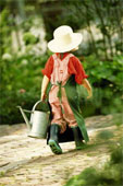 Gardening - Young girl carrying watering can from garden