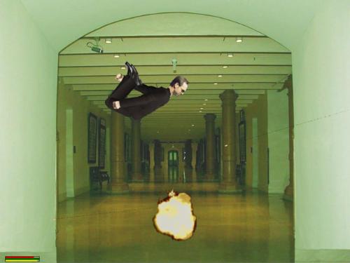 Matrix - The bad man from the Matrix with the black glasses is doing some flip  in the air and there is fire under him.