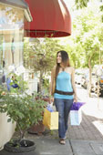 Shopping - Young Hispanic woman holding shopping bags and window shopping