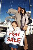 Kids - Young girl with a doll leaning on a for sale sign parents in the background