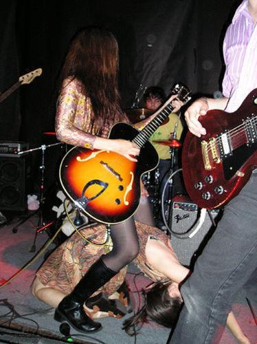 playing guitar - a woman playing guitar with her band.