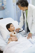 Hospital -  Female doctor using stethoscope on girl in hospital bed