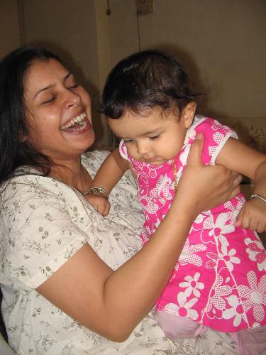 me and my baby - this is me and that's my baby in my arms . she is so naughty thats it was so difficult for me to hold her in my arms. this is her room and i was playing with her. this picture is cliked by my hubby. my pictures are very less becasue i am always cliking her with anyone and alone also. but i find very difficult to clik her with me myself. my hubby then to tries it and is uccessful also but i am not that skilled in it. i can take of my own and hubby together standing but this baby is so mischivious and naughty that she dont even give me time to blink my eye and i find that she has done something.