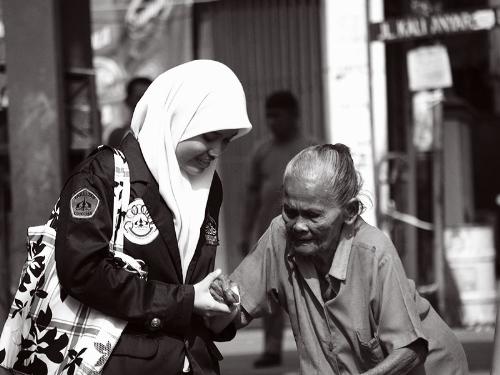 a lady helping an old woman - the old lady must have been too weak to stand up by herself; the good woman was kind enough to help her up. 