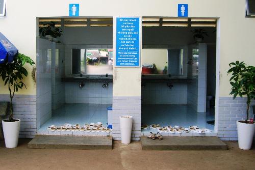 Toilet with change shoe request. - This toilet on the main road going north from Saigon requests users to remove their shoes and use those provided before entering the toilet. The notice is in Vietnamese and English. This was a new experience for me.