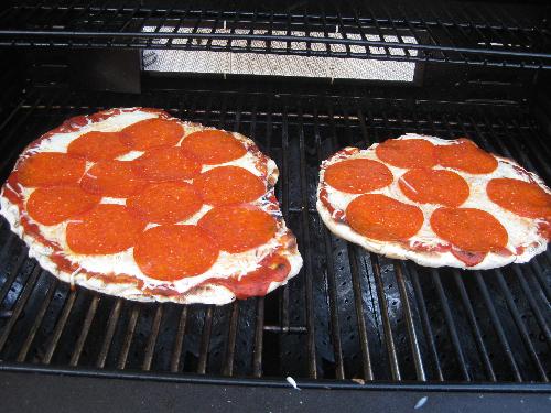 Grilled pizza - Two pizzas cooking on the grill.