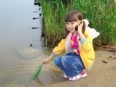 A little girl with mobile phone - A beautiful little girl using mobile on the riverside.