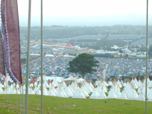 Tee Pees at Glastonbury Festival - For the chance of a superlative experience at the festival it was possible to pay extra, to have one&#039;s very own tee pee! Picture also gives view down to the centre of the festival, with all the music stages etc. In the background can be seen the now famous, fence or wall, to stop people hopping in for free!