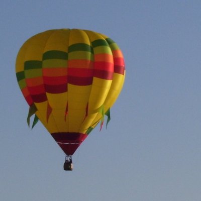 Hot Air Balloon - This bright yellow hot air balloon has colorful flags hanging off the sides as it flies over Jackson, Michigan during the Hot Air Jubilee