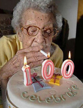 Happy 100th birthday - A 100 year old woman lighting a cigarette using the candles on her 100th birthday birthday cake