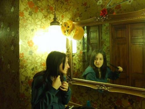 Mirror, Mirror. - A picture my brother had me model. It was before the movie Mirrors came out, so no, it does not follow it to detail if that is what you had in mind. But on one side i am a happy girl, on the other i am ready to kill myself, ha ha. I think it is amazing. Especially how the mirror looks a bit antique, (if you do not look at my pimp hat hangin from the corner, ha ha.)