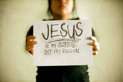Jesus Is My Savior... Not My Religion! - A woman holding a paper that says 'Jesus is my Savior, Not My Religion'.