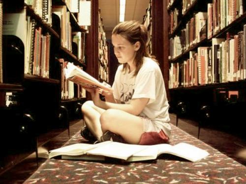 a girl studying in the library in the middle of bo - a girl studying very hard in the school library