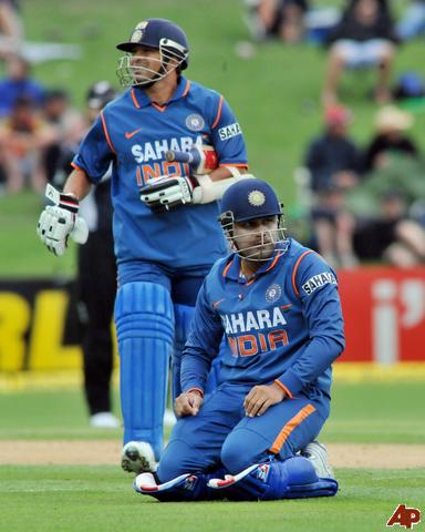 Virender Sehwag, Sachin Tendulkar - India's virender sehwag keels down after tripping gets support from sachin tendulkar against NewZealand in their 1st one day international cricket match at Mclean park in Napier