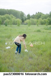 awareness - a women picking up the plastics from the park