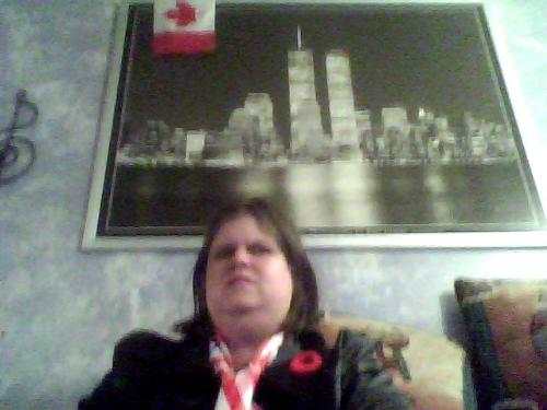 My NY Skyline picture, and me sitting underneath i - You can see my picture in the background. This takes up an entire wall in my apartment. You can also see the top of my long American flag scarf, where it is tied around my neck. I could not get far enough away with the webcam to get more of my scarf ANd the picture, but here you can see a bit of both.