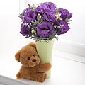Bear hugging flowers - purple flower with a stuff bear attached to the flower vase.
