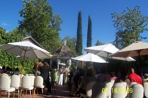 Outdoor Wedding in the Hot Hot Summer Heat - Wedding being held outdoors with 100 degree temperature, too hot to sit in the chairs so the wedding attendees took a sit along the sides where there was shade.