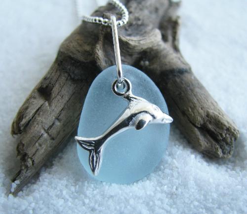 Riding Waves- Soft Blue Dolphin Sea Glass Necklace - This soft light blue sea glass gem is accented with a small sterling silver dolphin charm. The pendant hangs on an 18' sterling silver ball style chain. This pretty light blue piece of sea glass measures 5/8' in length.