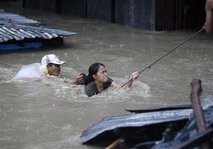 Typhoon Ondoy - A resident helps a woman evacuate during flooding in Bocaue outsirts beside a highway north of Manila.