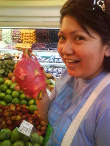 woman with dragon fruit  - at the grocery buying fruits