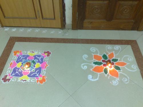 Diwali Rangoli - Rangoli, also known as Alpana, Kolam and by other names is a traditional art of decorating courtyards and walls of Indian houses, places of worship and sometimes eating places as well. The powder of white stone, lime, rice flour and other paste is used to draw intricate and ritual designs.   Although Rangoli art is Maharashtrian in origin, it has become quite popular all over the country. Each state of India has its own way of painting Rangoli. One characteristic of Rangolis is that it is painted by commoners. On some special occasions like Dipavali it is painted in every home, with or without formal training in Rangoli art. The art is typically transferred from generation to generation and from friend to friend.   Traditionally Rangolis are painted or created out of colored sand/rice powder. A symmetrical pattern or picture of Gods, Goddess, Dancers, Diyas etc. is drawn and colored rice powder/sand is then layered on top to form a picture. A symmetrical rangoli pattern can be drawn on paper or card and then decorated by children with crumpled tissue paper.   Spaces can be created within the rangoli design to place diyas. One can also use flower petals of different colors such as golden marigolds, bright red roses to add that extra dimension to the pattern. With a little bit of imagination, a dash of aesthetic sense and dollops of patience, one can create a piece of art with colors.   Most of the patterns are circular indicative of the endlessness of time. The day-to-day Rangoli patterns are simple or intricate. The most common rangoli designs start with dots which are connected to form lines and other geometrical shapes such as swastika, aum, stars, squares, circles, triangles etc. These geometrical patterns must be formed in a continuous, unbroken lines.