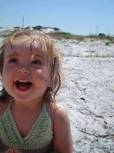 Girl at the beach - Little girl on the beach, laughing at the camera in a green and white striped bathing suit.