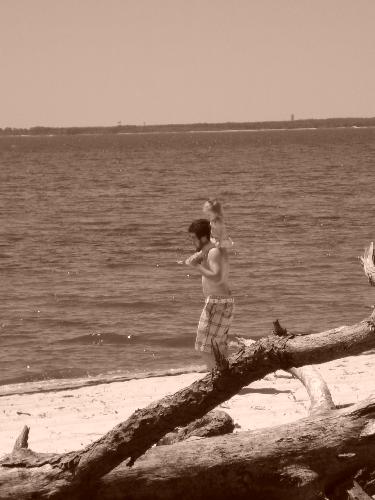 dad with daughter on shoulders - Dad with daughter on his shoulders at the beach. Sepia in color.