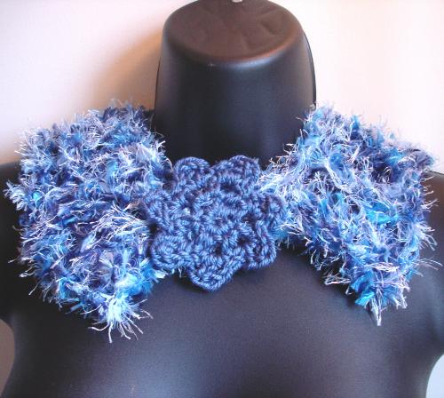 Knitted Neck Warmer in Shades of Blue - This is my warm & cozy hand knitted neck warmer. It was knitted with a combination of fun fur, feather boa, and soft acrylic yarn, on a super-size needle. It closes in the front with a hand crocheted flower 'button' & loop.