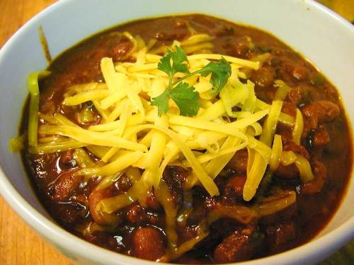Chili - A hot bowl of chili topped with shredded cheddar cheese.