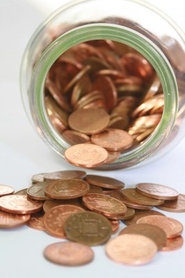 Counting The Pennies - An open jar of pennies cascading from a jar.