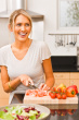 Cutting Vegetables - This is the image of a young happy woman cutting vegetable in her kitchen in a good mood.